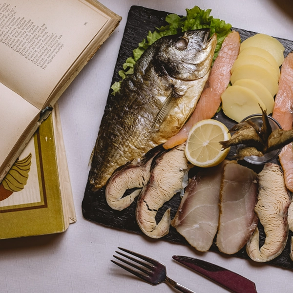 Benefici del mangiare pesce fa bene al cuore varietà di pesce su tagliere con limone e insalata