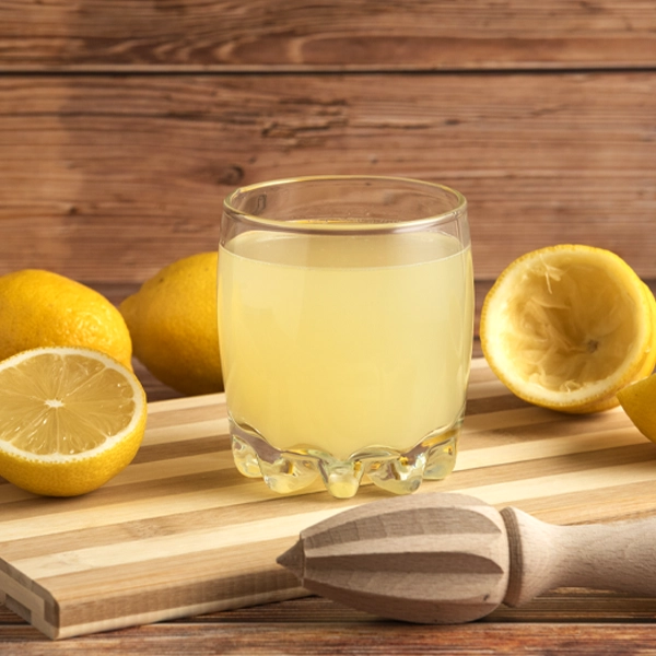 Dieta del limone per disintossicarsi dopo le vacanze bicchiere con succo limone su tagliere con limoni