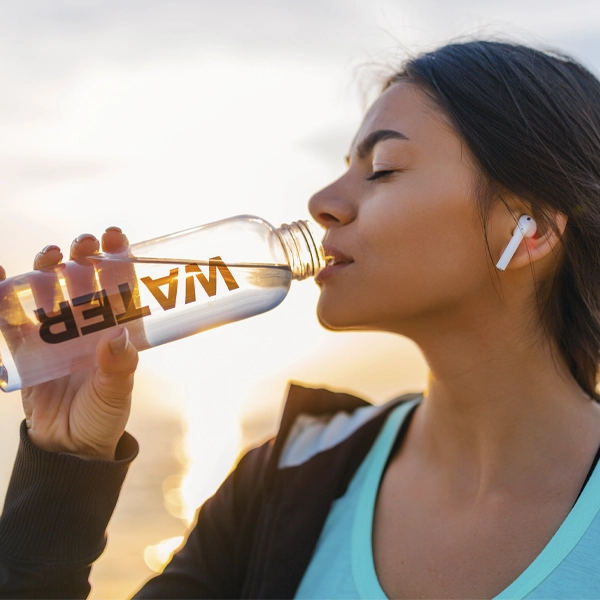 bere acqua ogni ora per accelerare il metabolismo ragazza sportiva al tramonto mentre beve acqua e ascolta musica